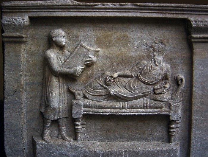 400-luvulta peräisin oleva reliefi Valerius Petronianuksesta ja hänen orjastaan, joka pitelee käsissään kirjoitustaulua. 