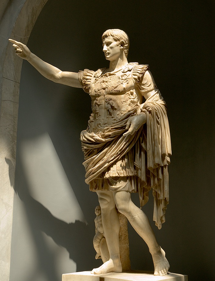 Tämä on luultavasti tunnetuin kuva keisari Augustuksesta. Tämä upea veistos on Vatikaanin museon kokoelmissa ja se tunnetaan nimellä Prima Portan Augustus. Veistos näyttää Augustuksen valloittajana, maailmanrauhan tuojana ja kultaisen aikakauden aloittajana. Keisari seisoo rauhallisena ja vaikuttavana hahmona, ja hänen jaloissaan on vauva, Eros, joka muistuttaa Augustusta hänen jumalallisesta alkuperästään. Veistoksen tehtävä on kertoa, että keisarin ansiosta valtiojärjestys on sopusoinnussa jumalten luoman maailmanjärjestyksen kanssa. Augustus on syntynyt maailmaan pitämään huolen siitä, että jumalten tahto ja oikeudenmukaisuus toteutuvat maailmassa. Hän varjelee ihmiskuntaa vääryydeltä lopetettuaan sodat ja luotuaan uuden hallitusjärjestelmän. Veistoksessa voimme myös nähdä kiteytettynä Augustuksen jälkimaineen kaikkein merkittävimpänä kaikista Rooman keisareista. Hänelle kuuluu kunnia siitä, että sisällissodat loppuivat ja Roomaan koitti rauhanaika. Valokuvaaja tuntematon. 