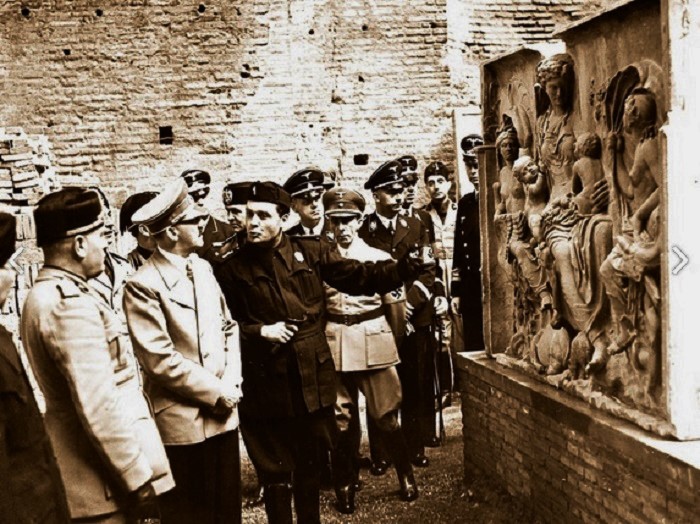 Benito Mussolini ja Adolf Hitler kuuntelevat oppaan selostusta fragmentista, joka esittää Saturnia Tellusta. Kuvassa näkyvät myös Joseph Goebbels, Heinrich Himmler ja Joachim von Ribbentrop. Kuva: Alinari Archives, Firenze. 